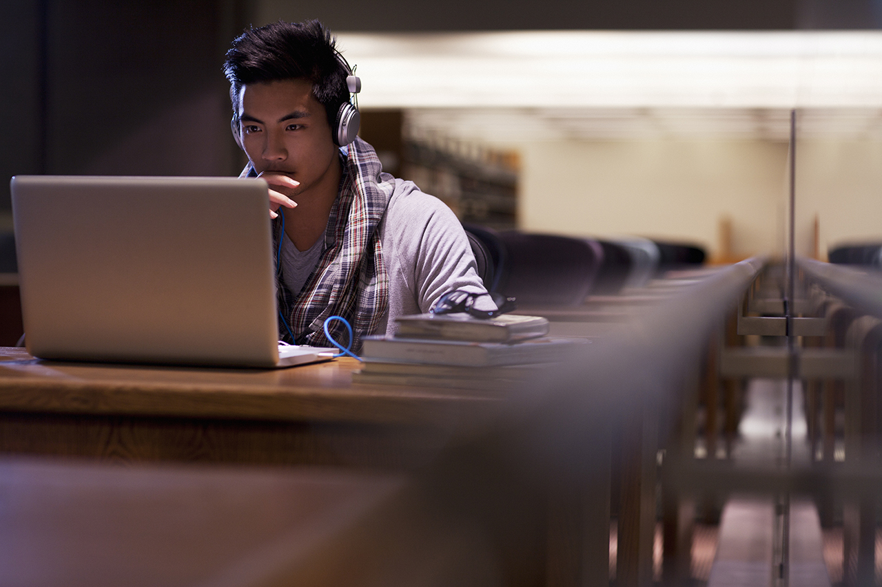 College student working on laptop in library