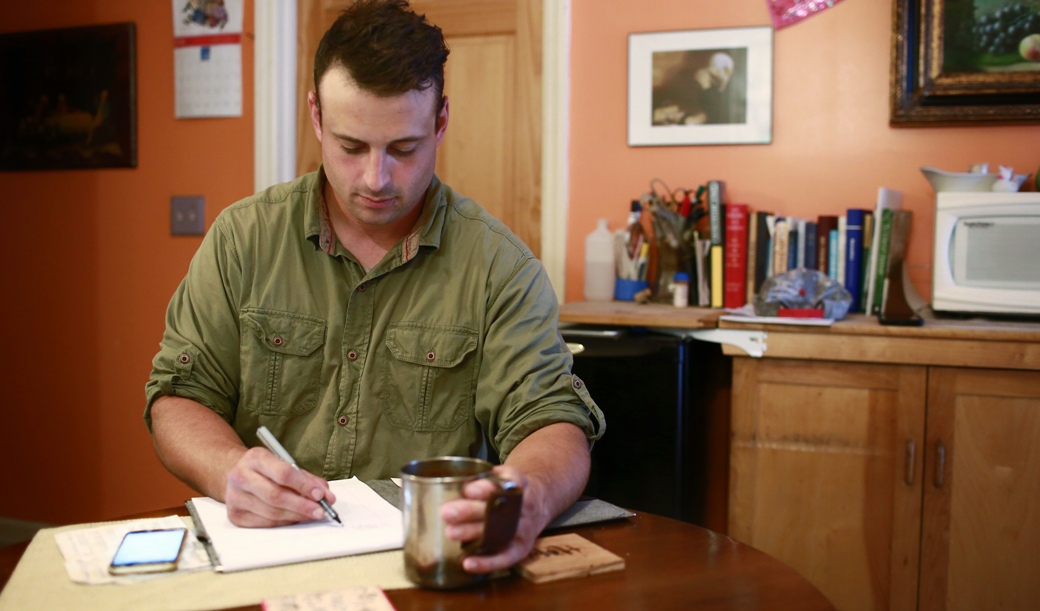 Man taking notes on a notepad at a desk
